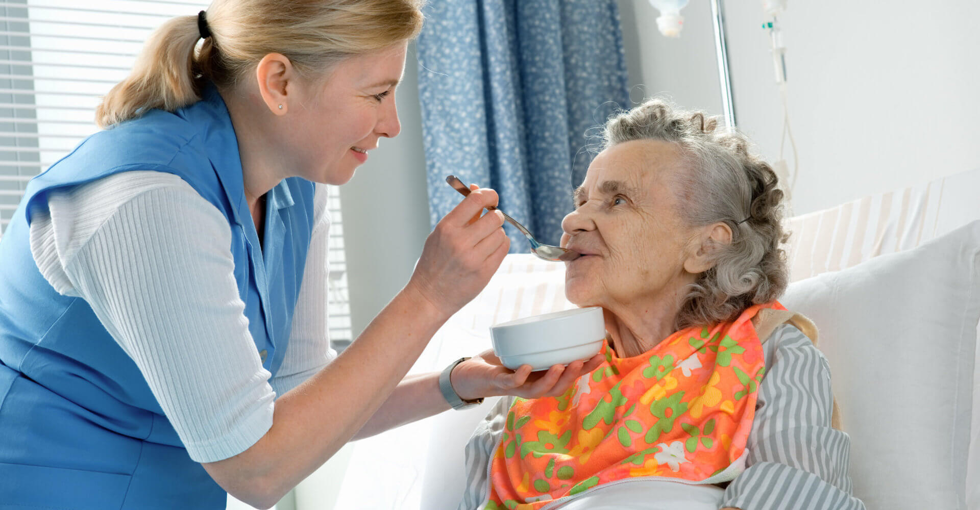 nurse helping an old lady with her meal